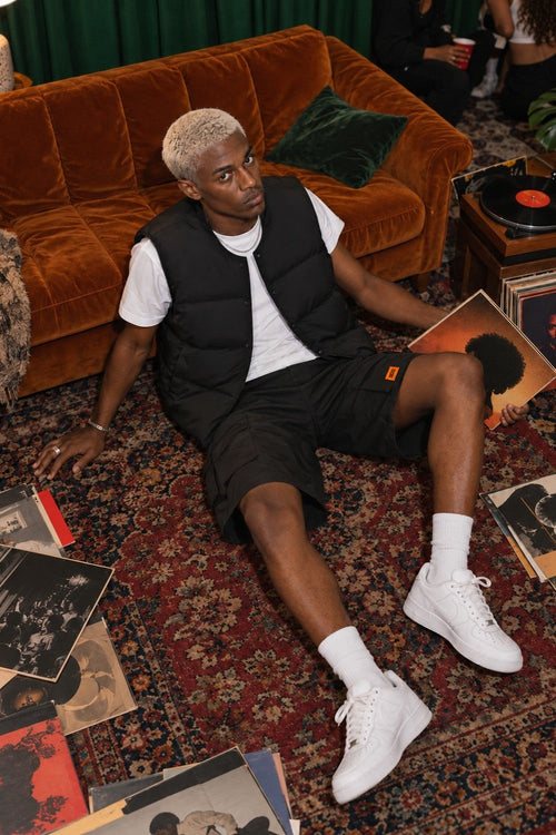 AJ Tech Cargo Short Black with Puffer Vest Black, on the floor with records