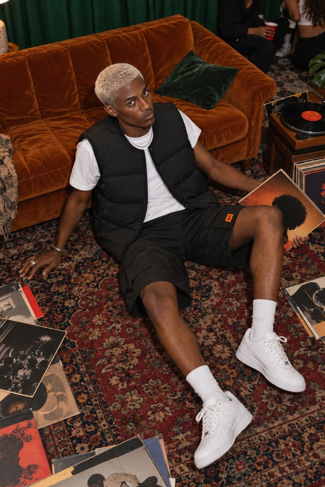 AJ Tech Cargo Short Black with Puffer Vest Black, on the floor with records