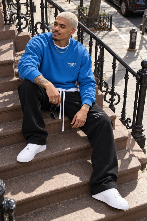 Legacy Sweatshirt Cobalt Blue, sitting on a New York stoop